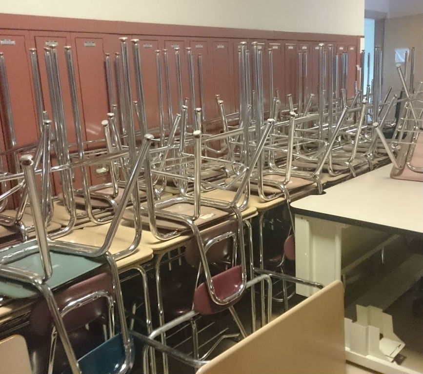 desks and chairs in the hallway of the school awaiting room to be cleaned